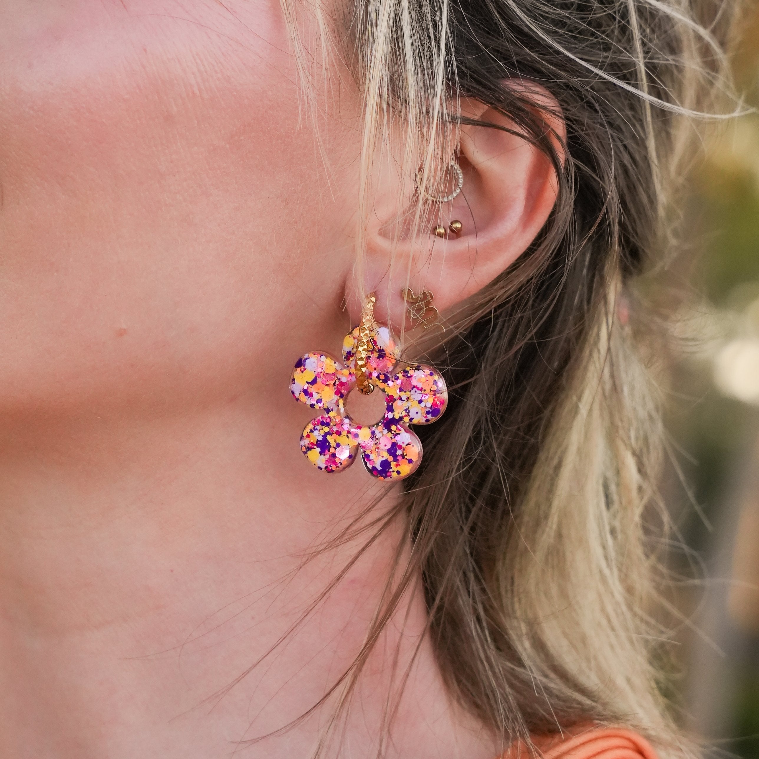 Créole fleur multicolore pailletée portée à l'oreille