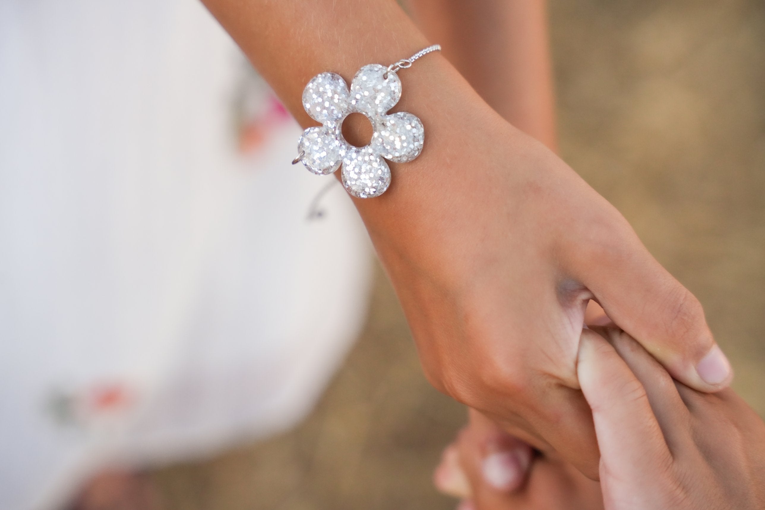 Bracelet fleur pailletée argentée porté au poignet